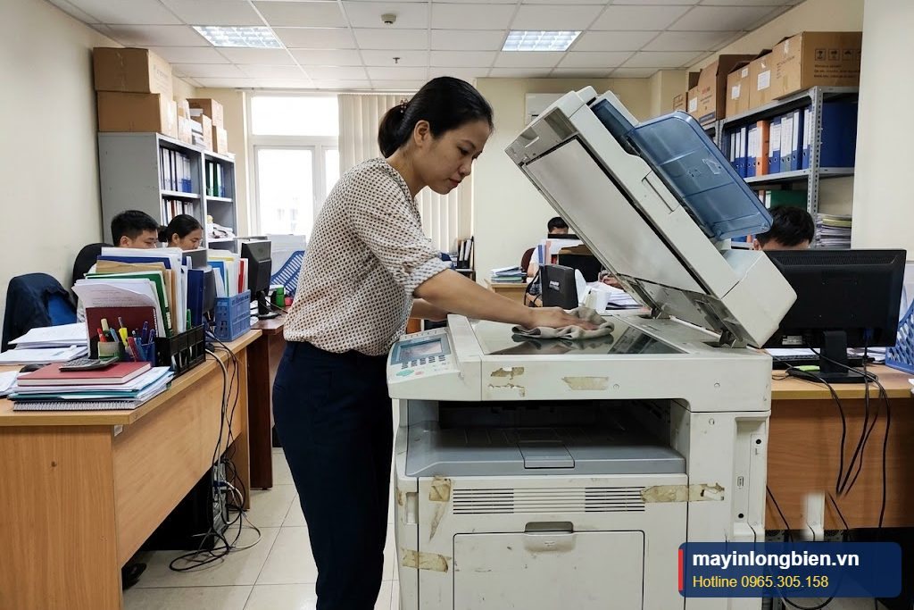 Nhân viên lau mặt kính máy photocopy hằng tuần