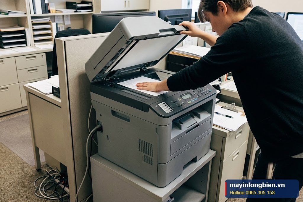 Máy photocopy đặt tại góc văn phòng, nhân viên đang sao chụp tài liệu Máy photocopy đặt tại góc văn phòng, nhân viên đang sao chụp tài liệu