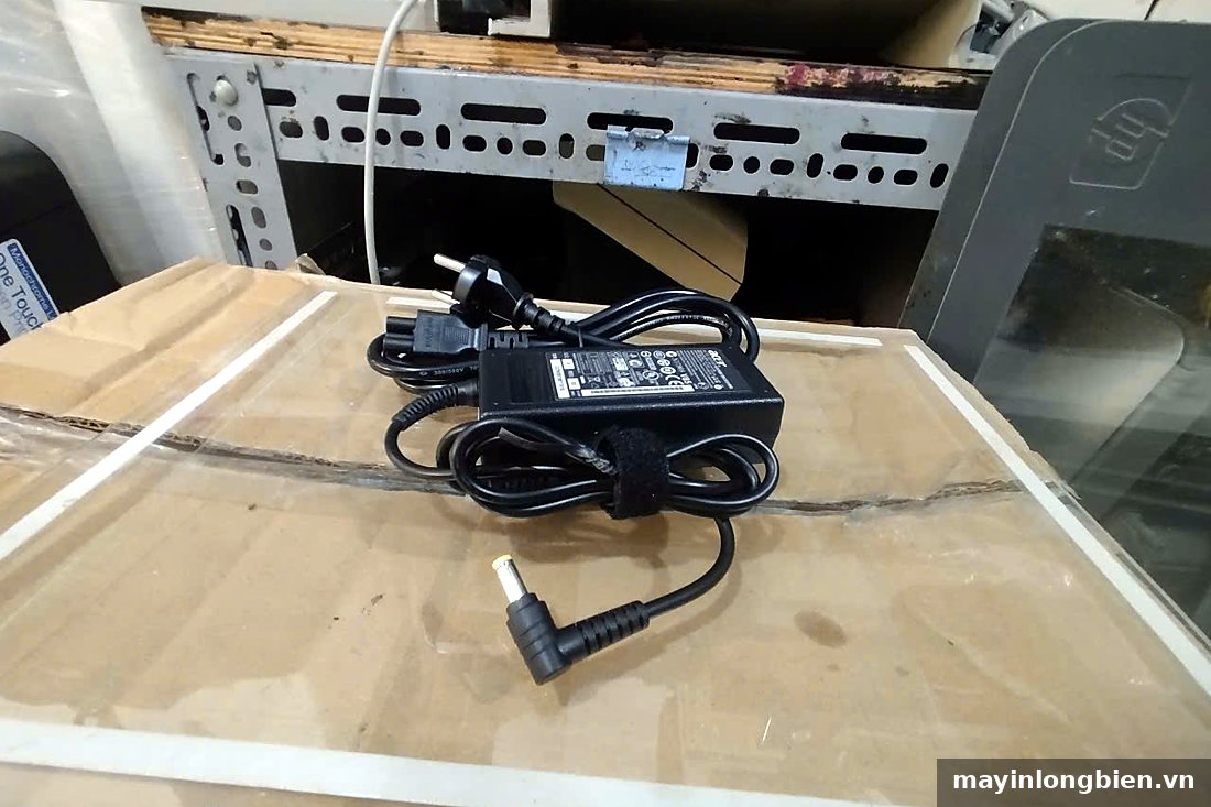 Bộ sạc laptop cuộn dây nguồn đặt trên mặt bàn Bộ sạc laptop cuộn dây nguồn đặt trên mặt bàn