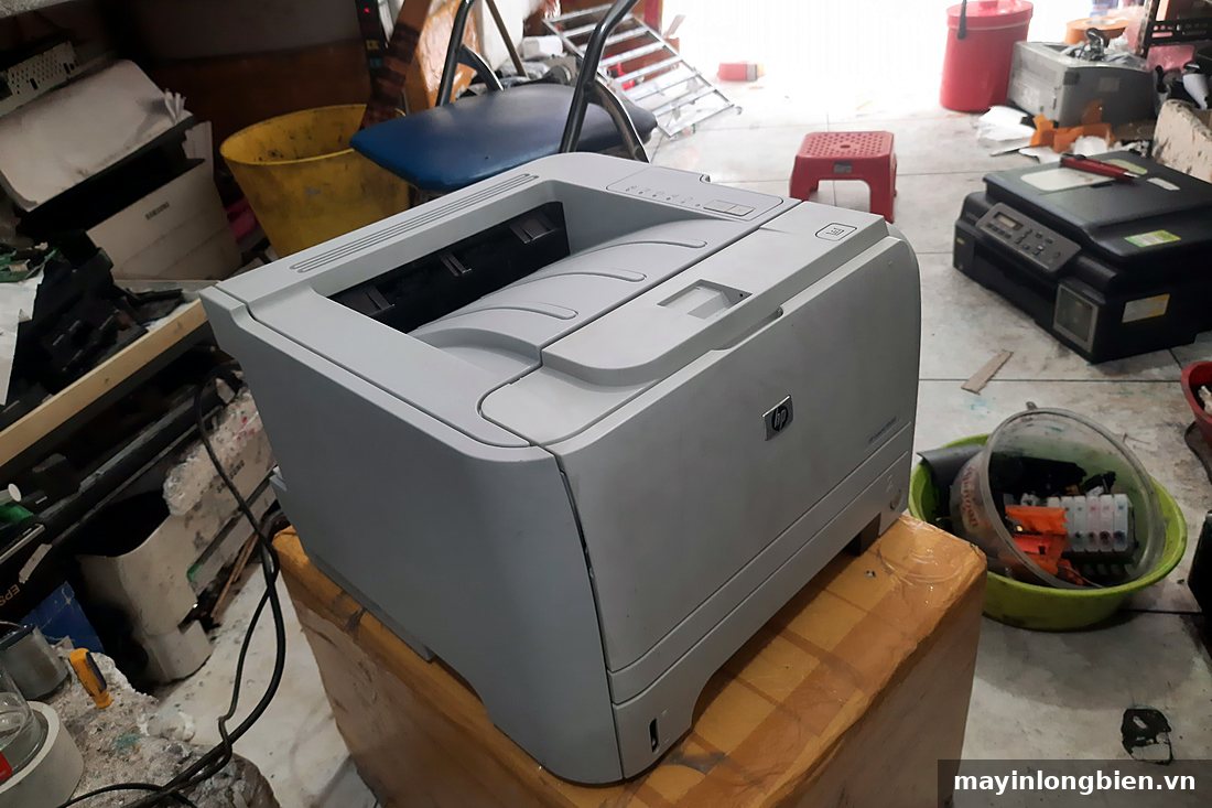 Máy in laser HP màu xám đặt trên bàn kê
